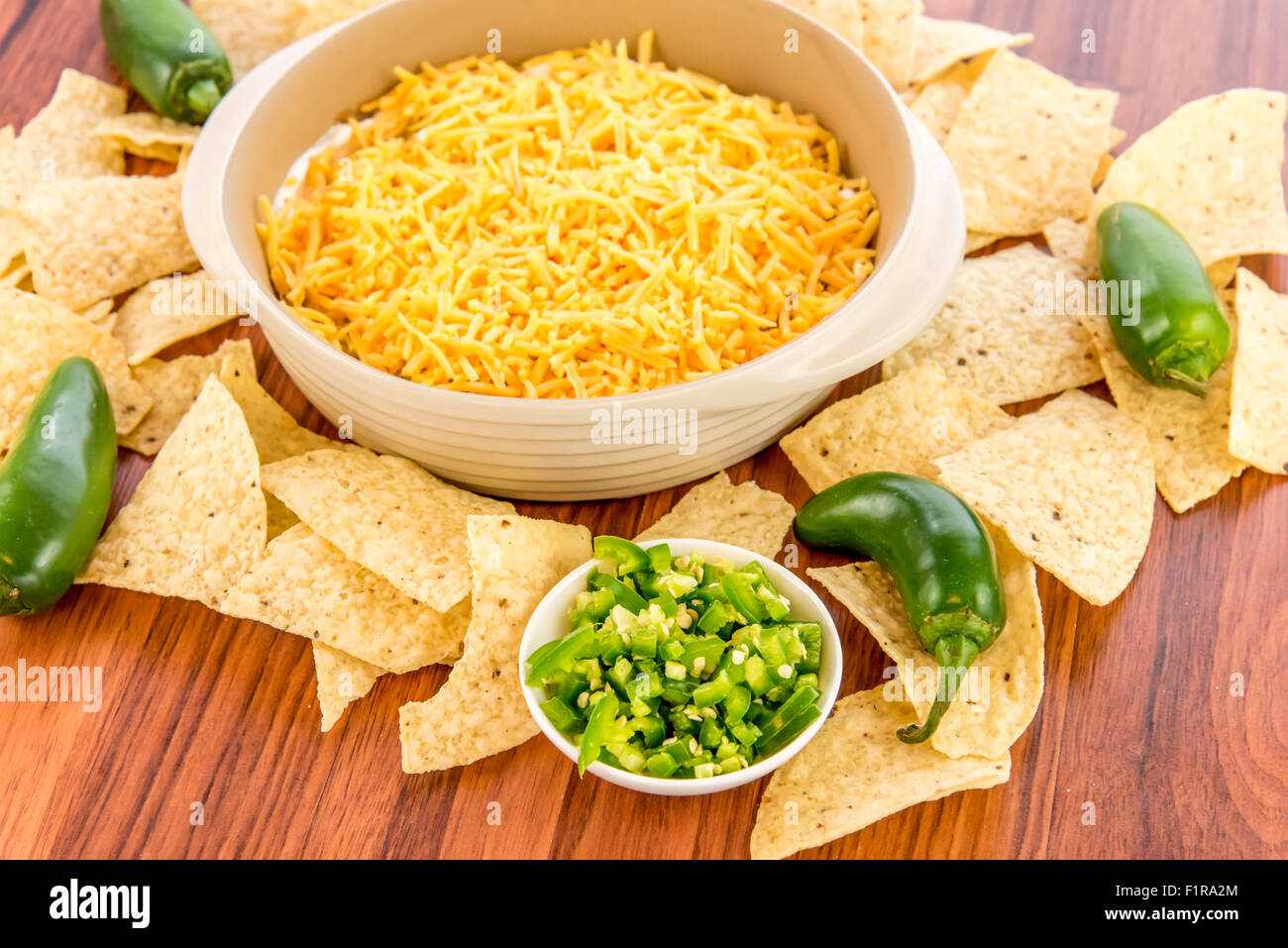 preparation of layered bean dip with jalapenos, sour cream and cheddar cheese Stock Photo