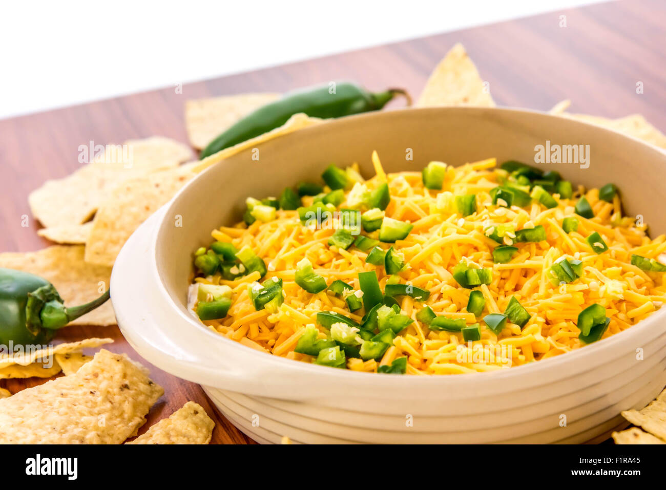 preparation of layered bean dip with jalapenos, sour cream and cheddar
