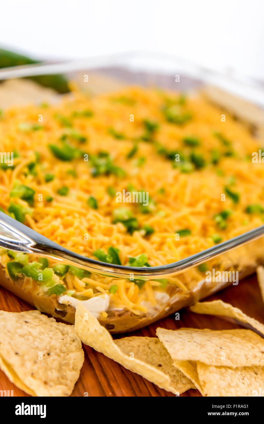 preparation of layered bean dip with jalapenos, sour cream and cheddar