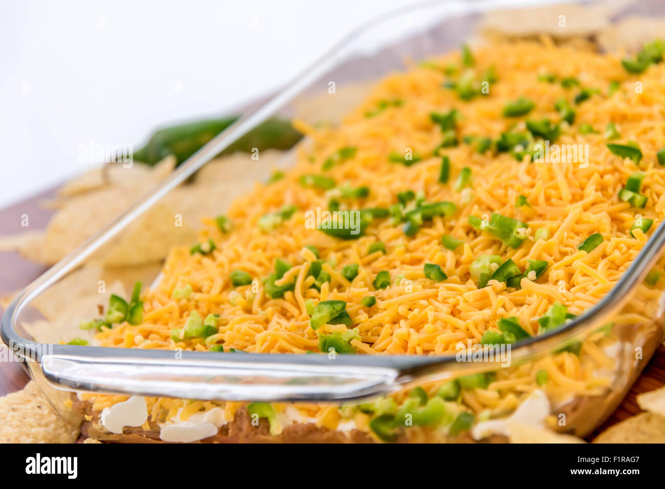 preparation of layered bean dip with jalapenos, sour cream and cheddar cheese Stock Photo