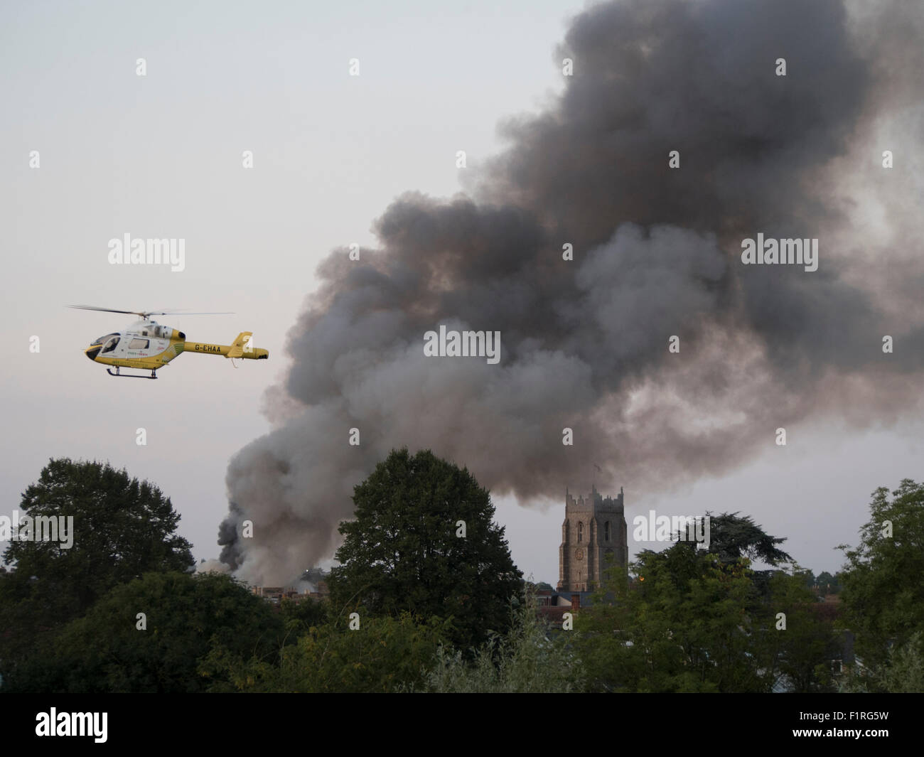 An air ambulance from the Essex and Herts air ambulance service hovers near a fire in the center of Sudbury, Suffolk, UK.. 2015. Stock Photo