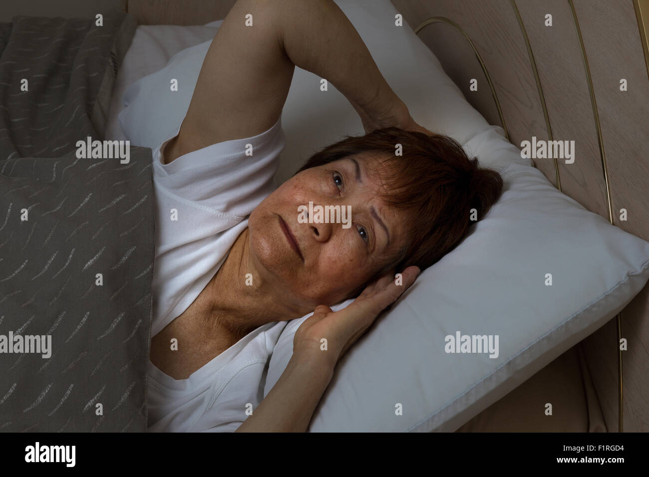 Close up of senior woman, eyes open looking upward, trying to fall asleep. Insomnia concept. Stock Photo