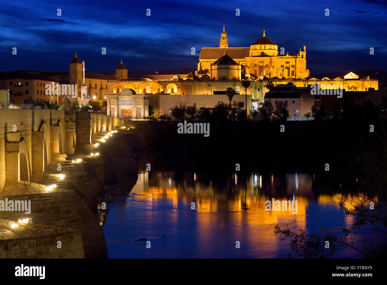 Cordoba Cathedral Mosque reflected in Guadalquivir River with Roman Bridge at twilight Stock Photo