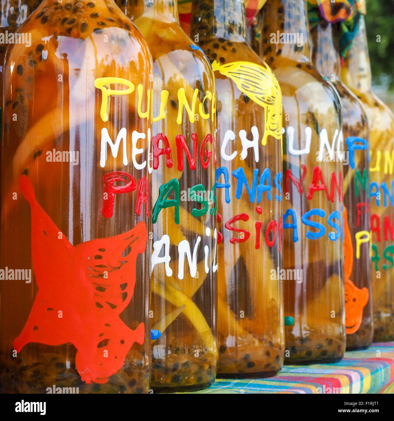 Traditional flavored rhum bottles on the desk of a market stall in Sainte Anne, Guadeloupe Stock Photo
