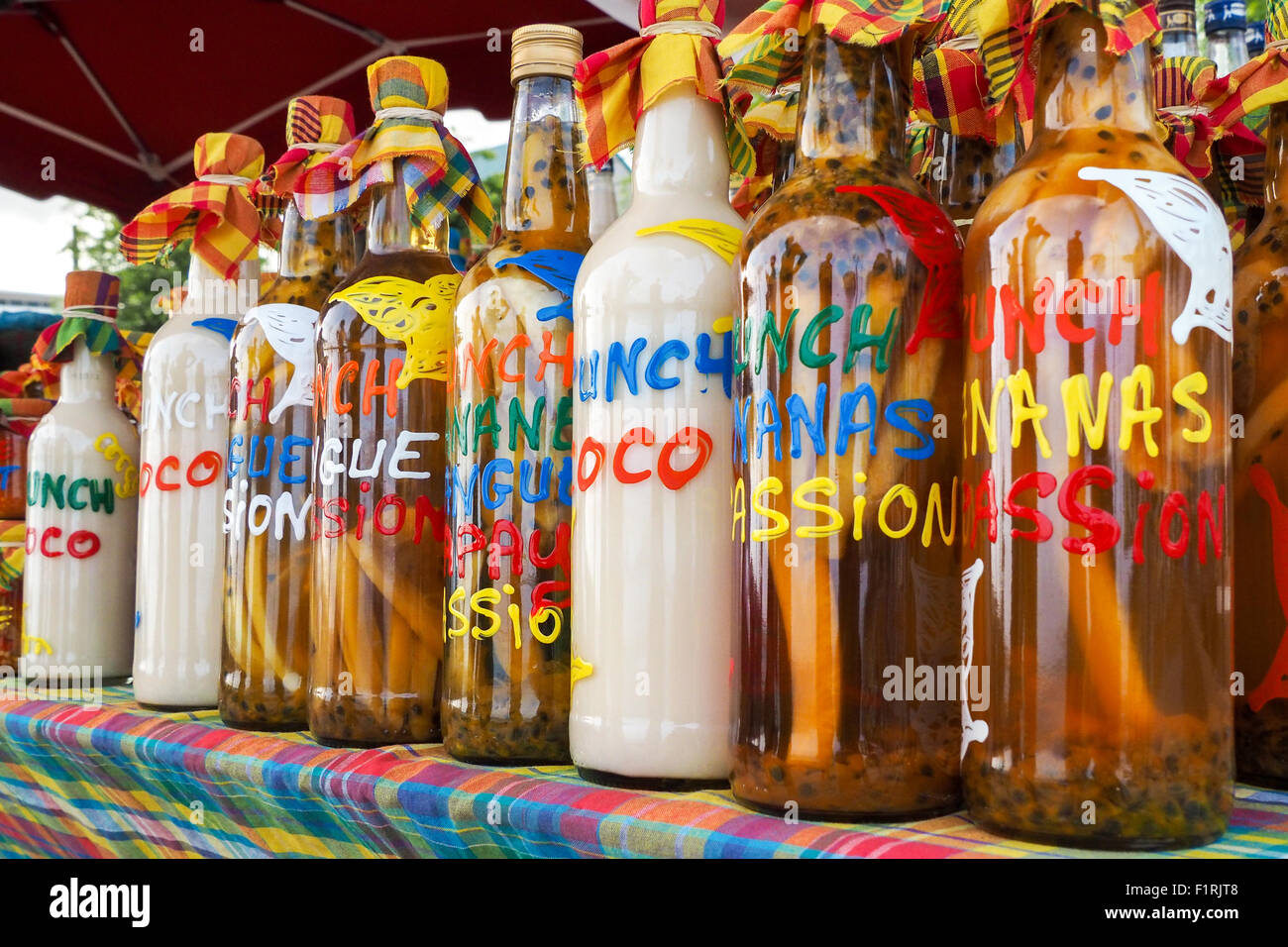 Traditional flavoured rhum bottles on the desk of a market stall in Sainte Anne, Guadeloupe Stock Photo