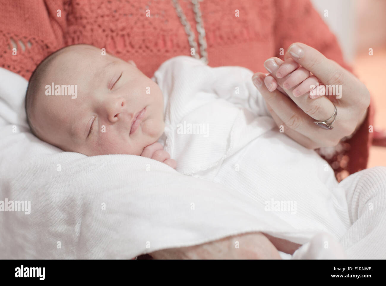 Cute newborn baby girl sleeping and holding grandmother's hand Stock Photo