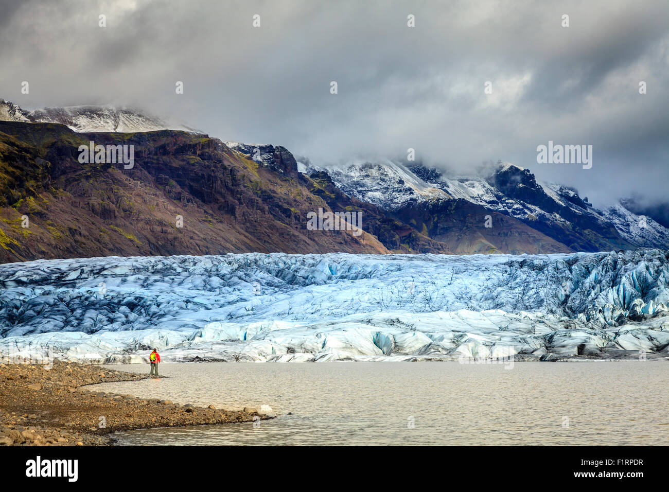 Hiker on the shore of Fjallsarlon lagoon at a glacier terminus in the south of Iceland Stock Photo