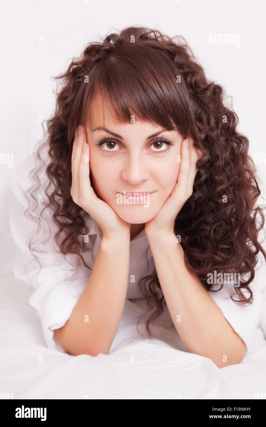 Beautiful young woman in white shirt lying on a bed Stock Photo