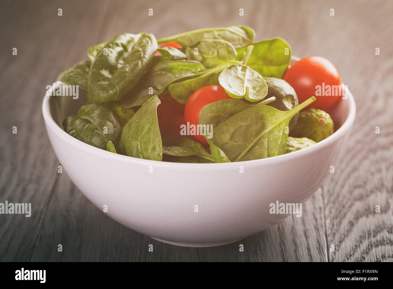 fresh summer organic salad with tomatoes cucumbers and spinach on wooden table Stock Photo