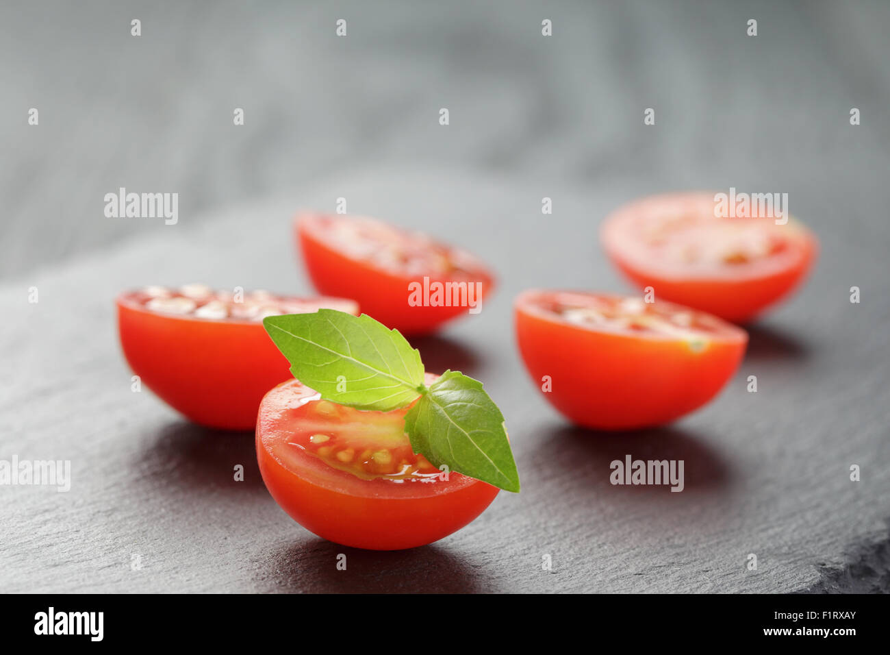cut in half cherry tomatoes on slate board Stock Photo - Alamy