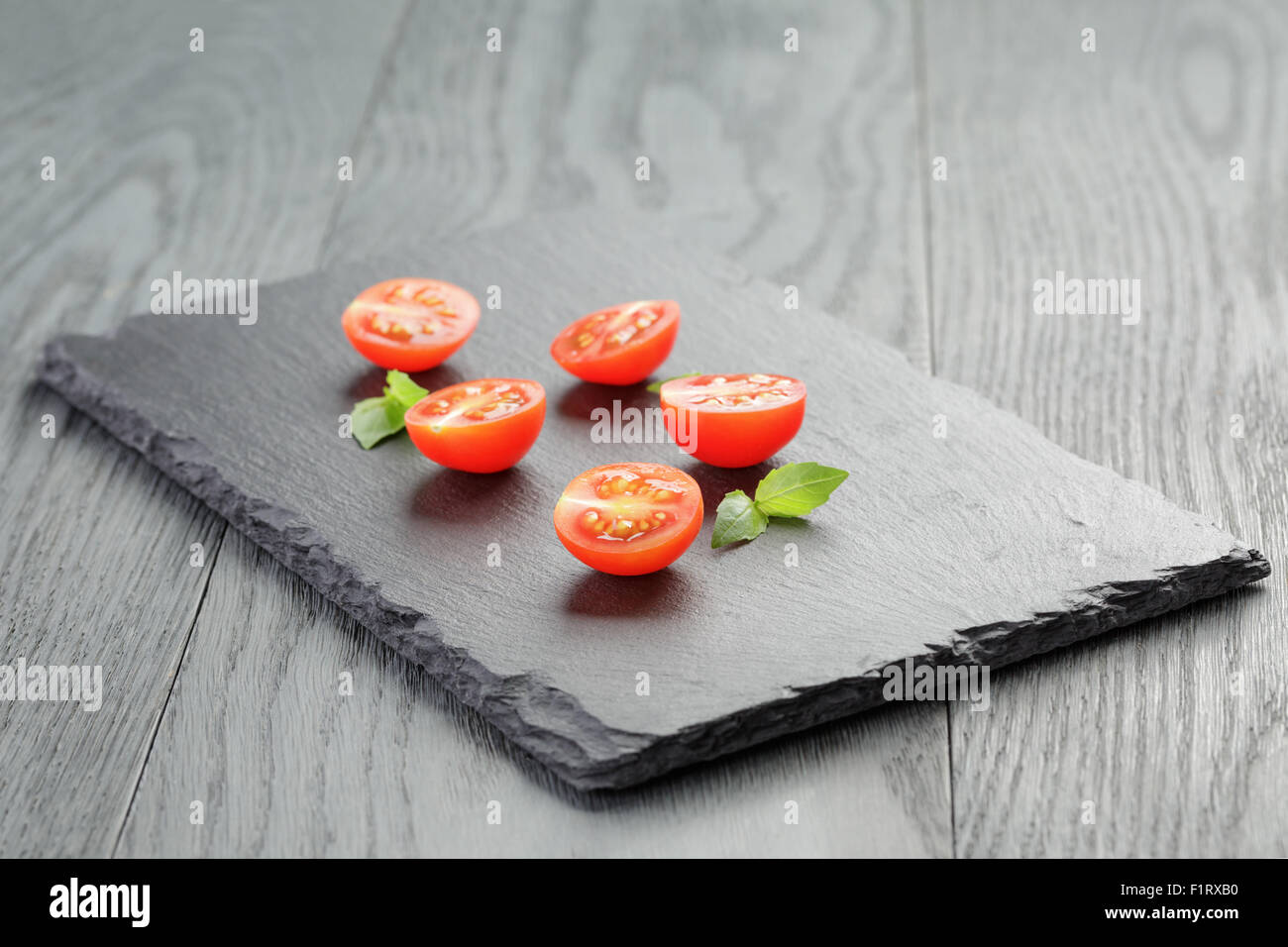 cut in half cherry tomatoes on slate board Stock Photo - Alamy