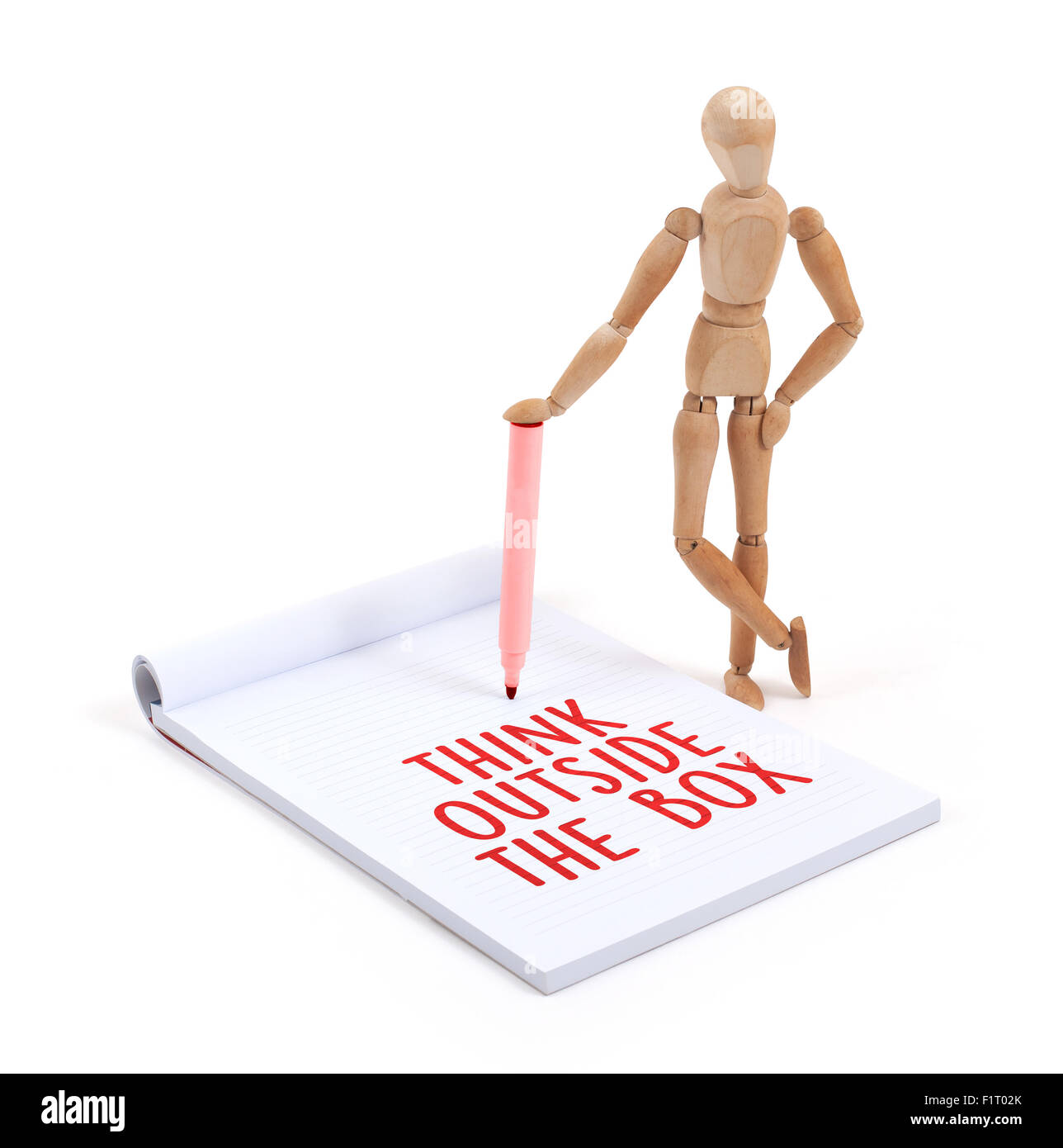 Wooden mannequin writing in a scrapbook - Think outside the box Stock Photo