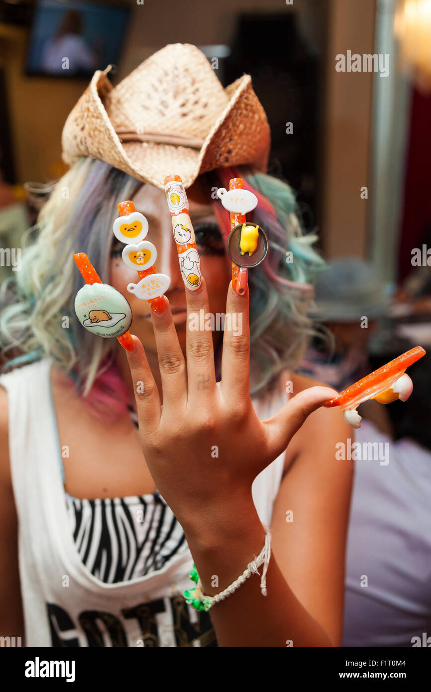 Erimokkori, a member of staff, shows off her nail art at the Ganguro Cafe & Bar in the Shibuya shopping area on September 4, 2015. Ganguro is an alternative Japanese fashion trend which started in the mid-1990s where young women, rebelling against the traditional idea of Japanese beauty, wore colorful make-up and clothes and had dark-skin. 10 Ganguro fashion girls work in the new bar, which offers original Ganguro Balls (fried takoyaki style sausage balls in black squid ink batter) on its menu. Ganguro Café & Bar also offers special services such as Ganguro make-up and the chance to take pu Stock Photo