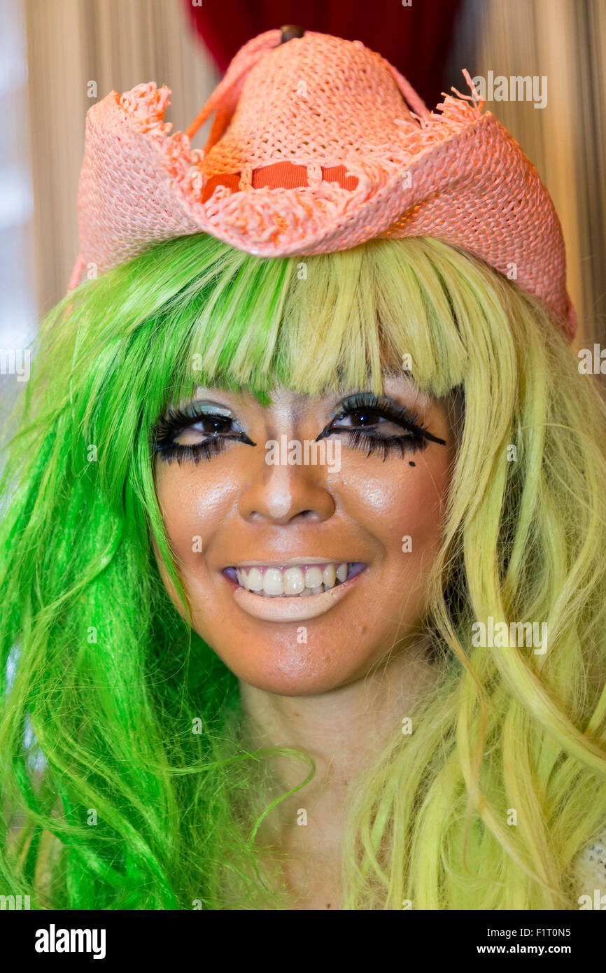 A female customer who has been transformed into a ganguro girl poses for pictures at the Ganguro Cafe & Bar in the Shibuya shopping area on September 4, 2015. Ganguro is an alternative Japanese fashion trend which started in the mid-1990s where young women, rebelling against the traditional idea of Japanese beauty, wore colorful make-up and clothes and had dark-skin. 10 Ganguro fashion girls work in the new bar, which offers original Ganguro Balls (fried takoyaki style sausage balls in black squid ink batter) on its menu. Ganguro Café & Bar also offers special services such as Ganguro make- Stock Photo