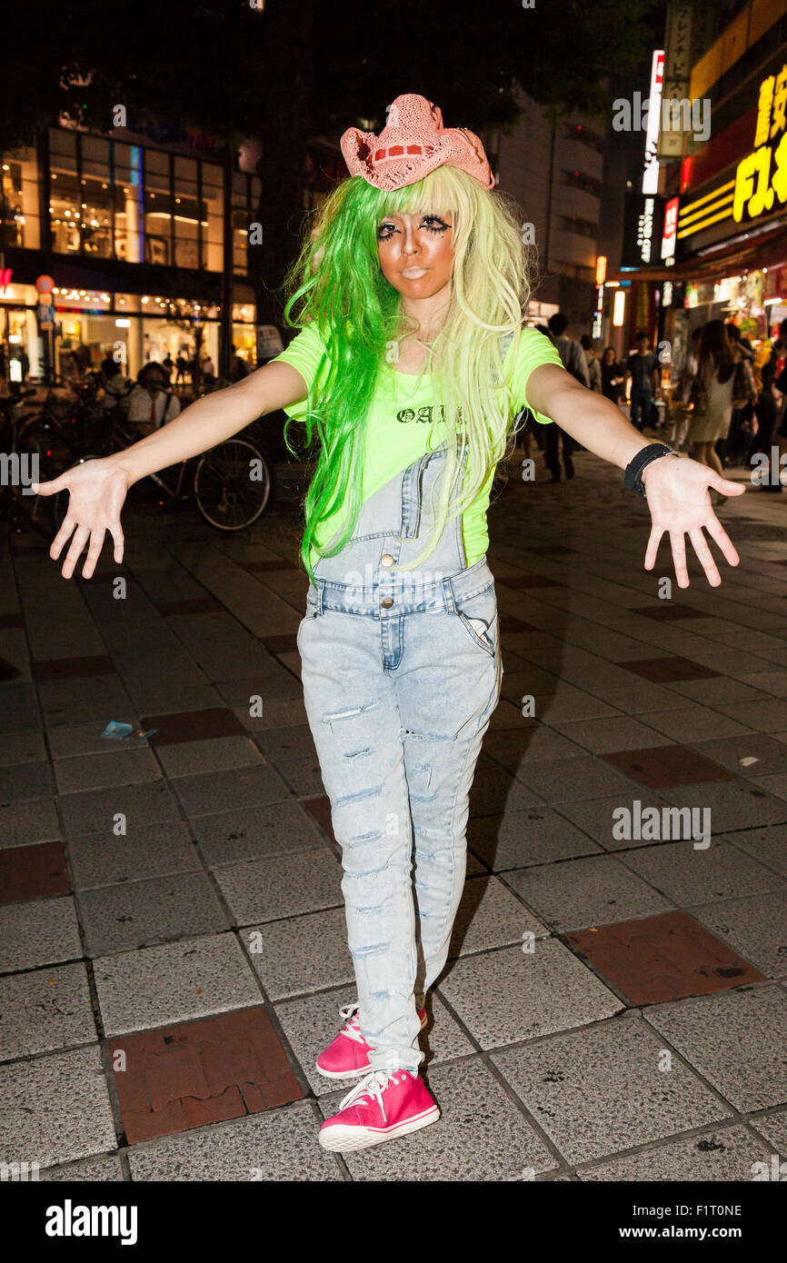 A female customer who has been transformed into a ganguro girl poses for pictures in the Shibuya shopping area on September 4, 2015. Ganguro is an alternative Japanese fashion trend which started in the mid-1990s where young women, rebelling against the traditional idea of Japanese beauty, wore colorful make-up and clothes and had dark-skin. 10 Ganguro fashion girls work in the new bar, which offers original Ganguro Balls (fried takoyaki style sausage balls in black squid ink batter) on its menu. Ganguro Café & Bar also offers special services such as Ganguro make-up and the chance to take Stock Photo