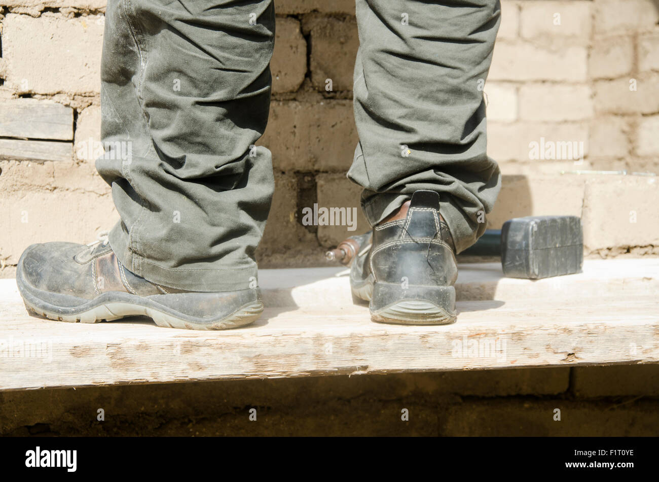 Close up of male boots dirty of work in the construction site and a hammer Stock Photo