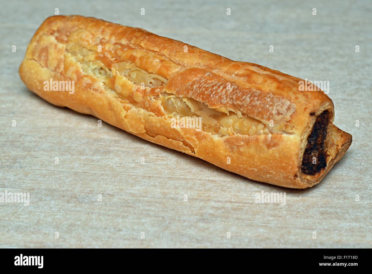 one crispy homemade sausage roll on a plain background Stock Photo