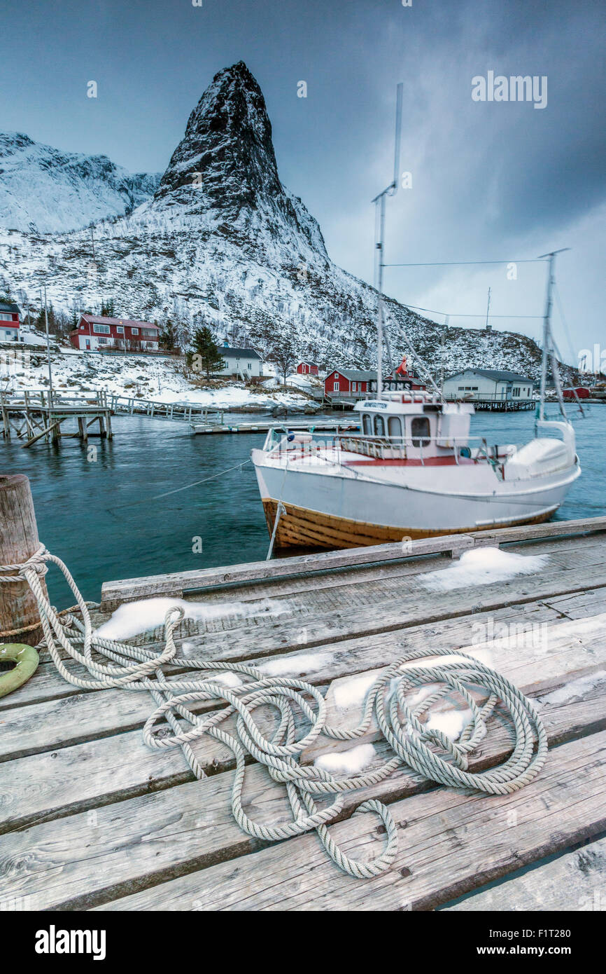 A boat moored in the cold sea in the background the snowy peaks, Reine. Lofoten Islands, Northern Norway, Scandinavia, Arctic Stock Photo