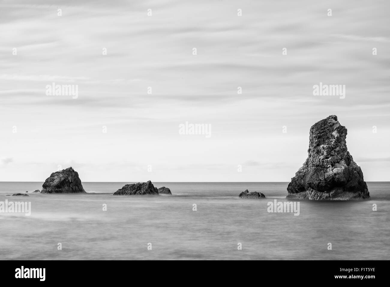 Beautiful long exposure peaceful landscape of rocks in sea in black and white Stock Photo
