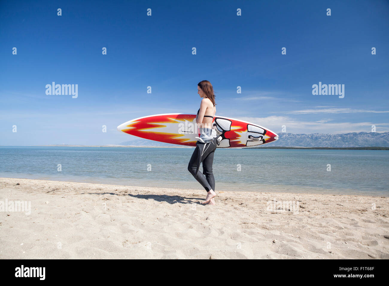 Woman carrying surfboard on beach Stock Photo - Alamy