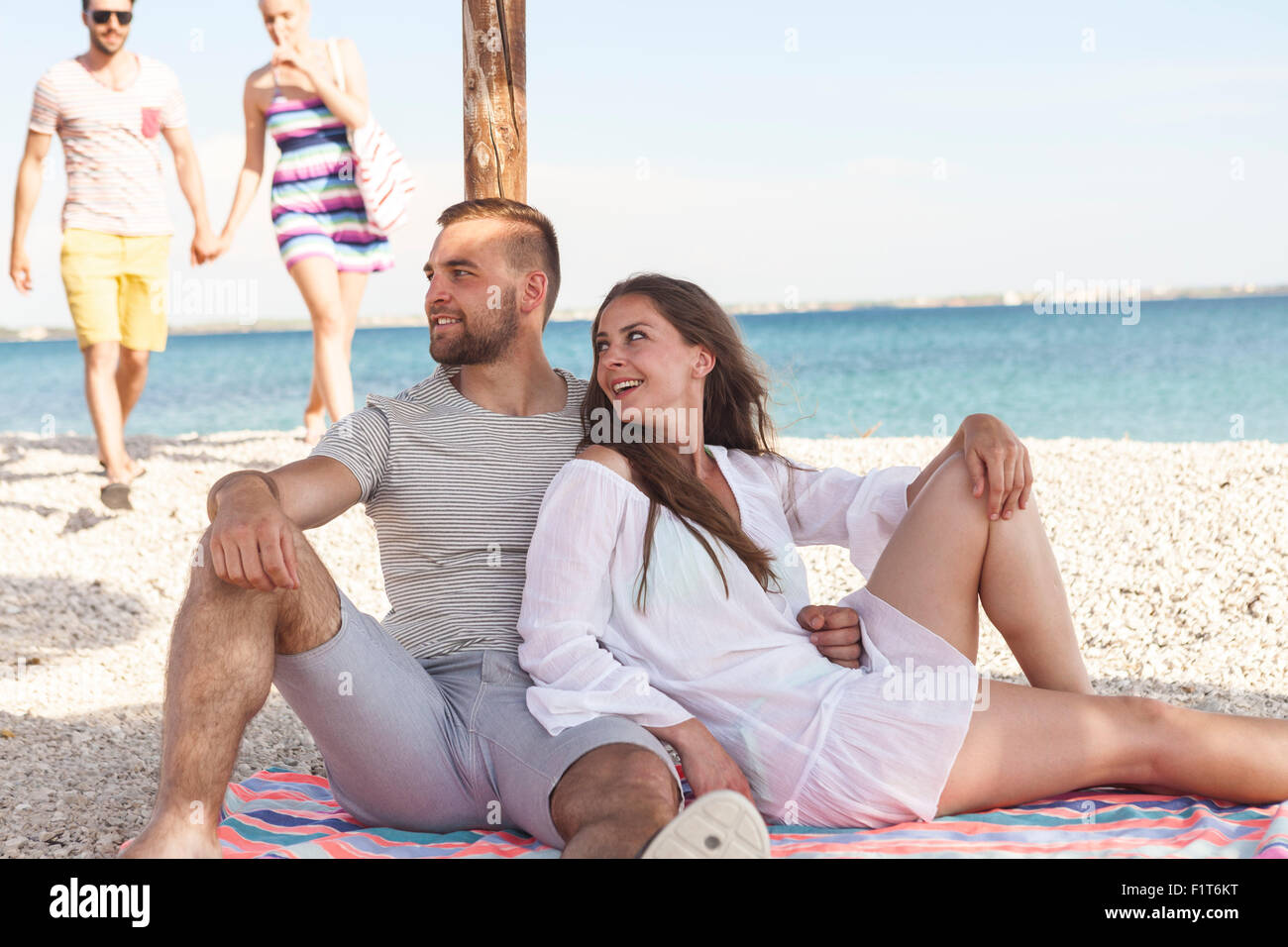 Young couple relaxes under beach umbrella Stock Photo