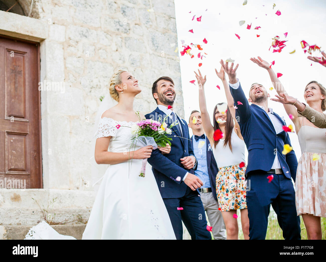 Guests throwing rose petals on bride and groom Stock Photo Alamy