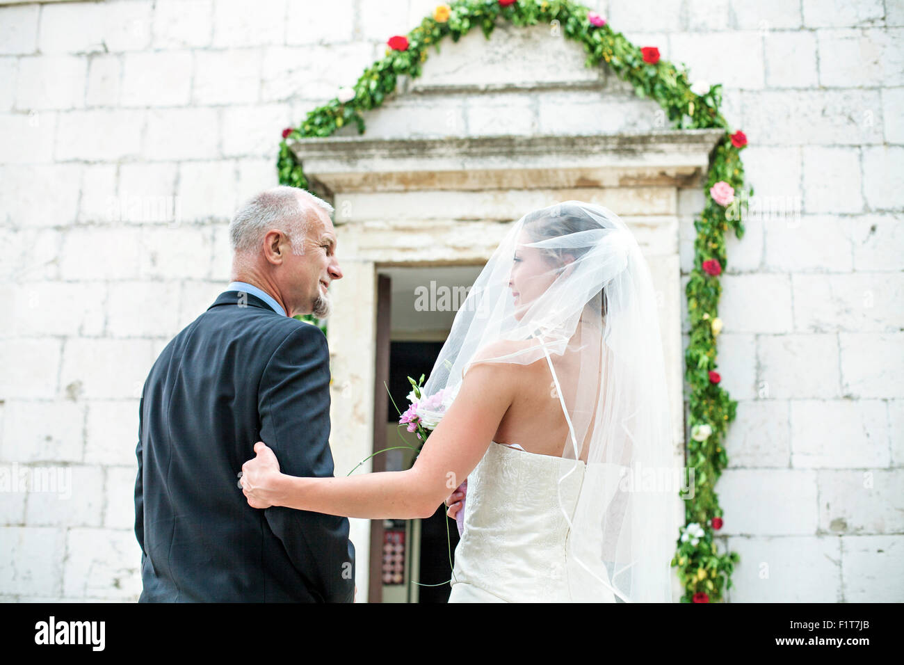 Father escorting bride to church, rear view Stock Photo