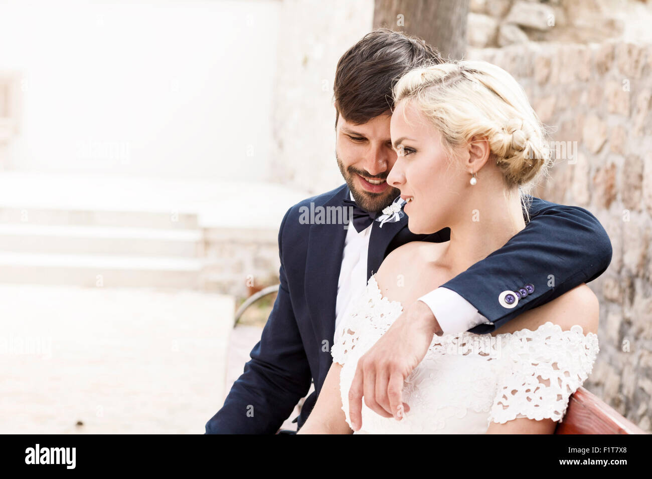 Happy bride and groom sitting on bench Stock Photo - Alamy