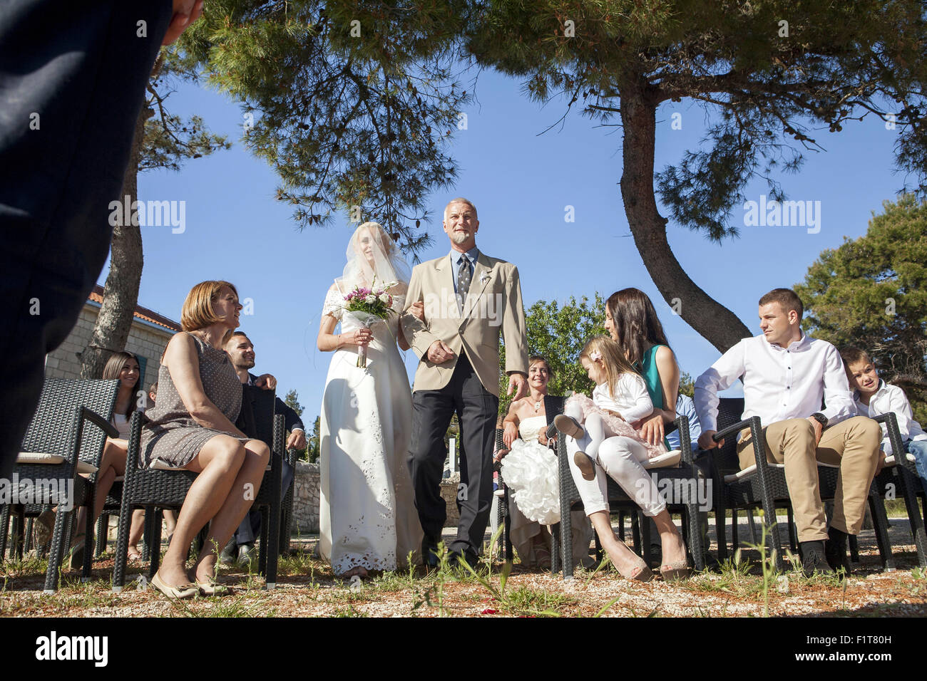 Father of the bride escorting bride at wedding ceremony on beach Stock Photo