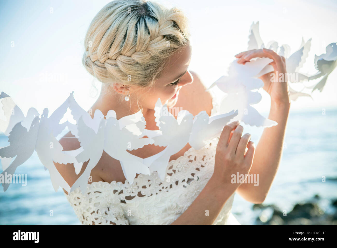 Bride playing with white paper cut out outdoors Stock Photo