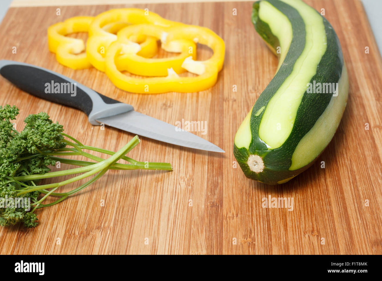 Cutting board with herbs sliced pepper zucchini and a knife. Stock Photo
