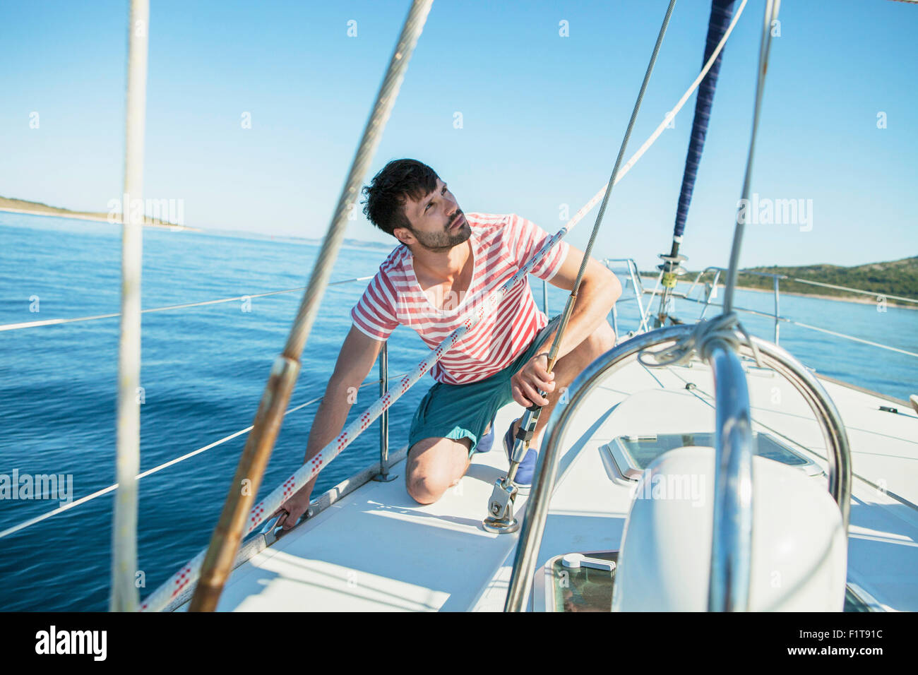 Man adjusting rigging on sailboat, Adriatic Sea Stock Photo