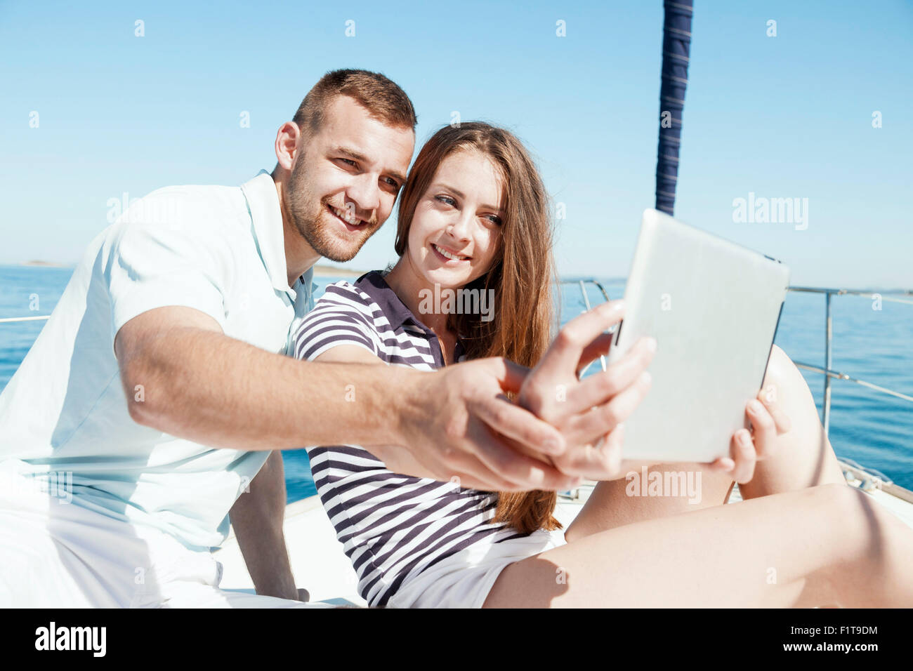 Young couple using digital tablet on sailboat, Adriatic Sea Stock Photo