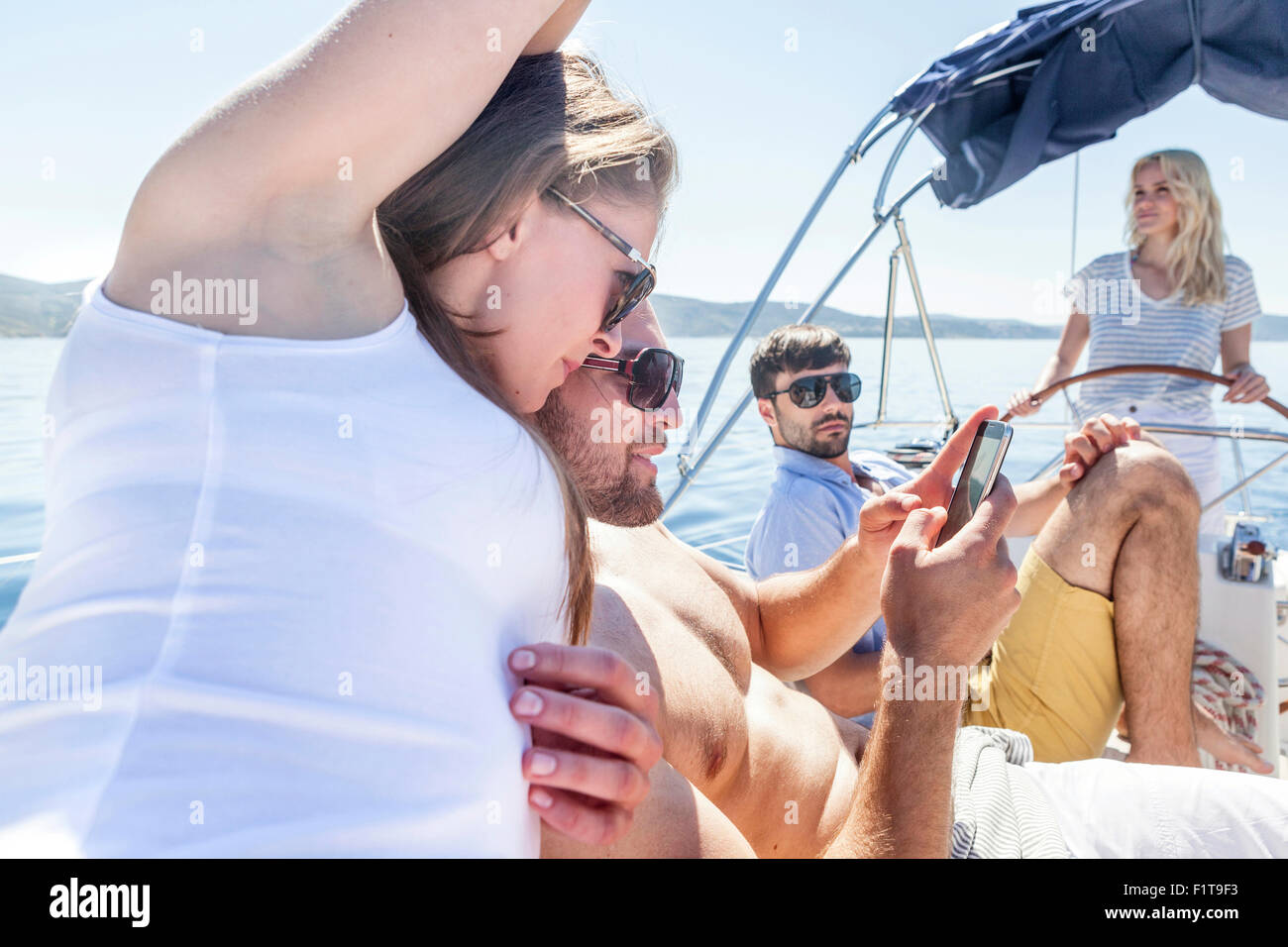Group of friends text messaging on sailboat, Adriatic Sea Stock Photo