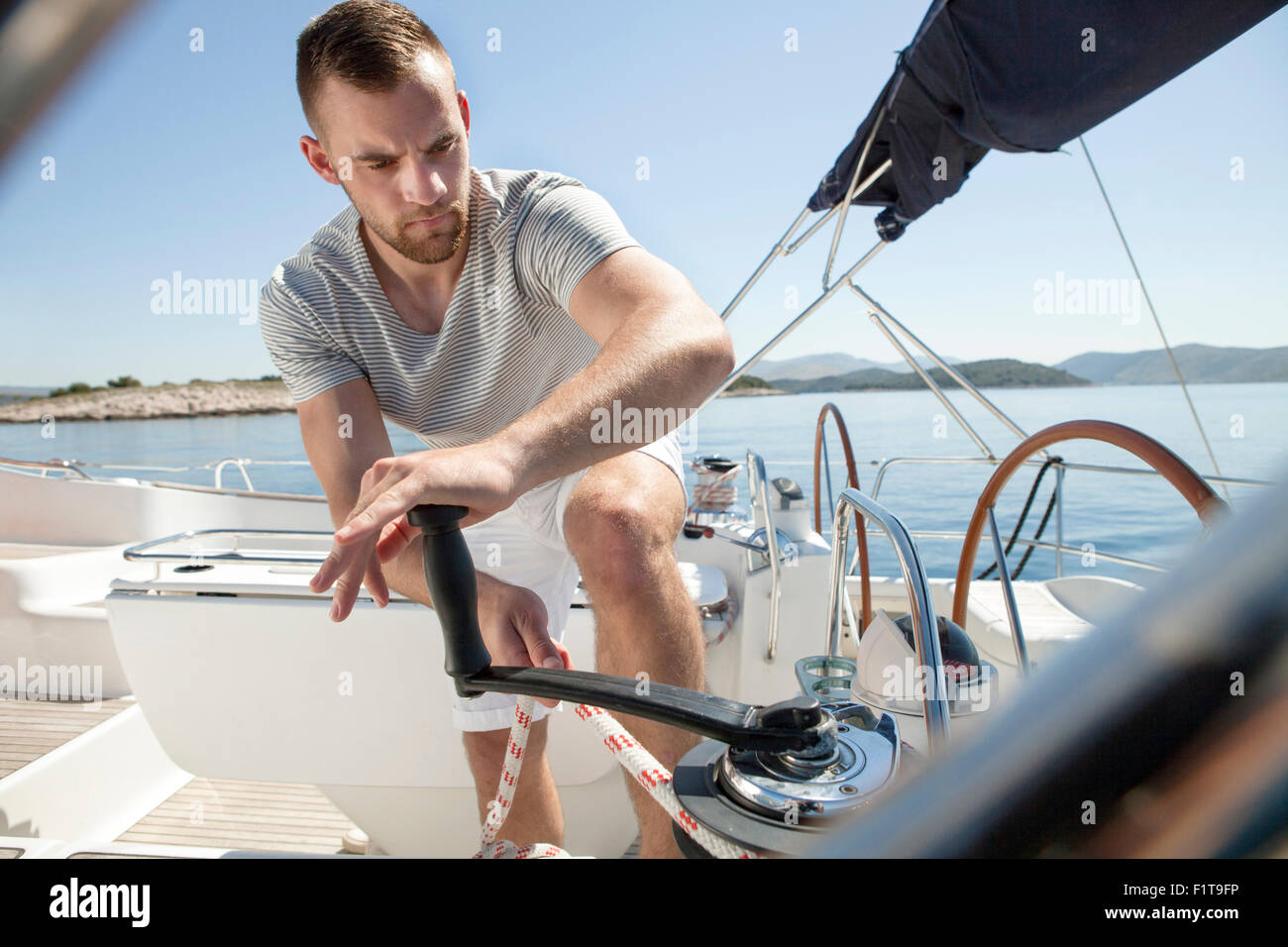 Man turning on cable winch on sailboat, Adriatic Sea Stock Photo