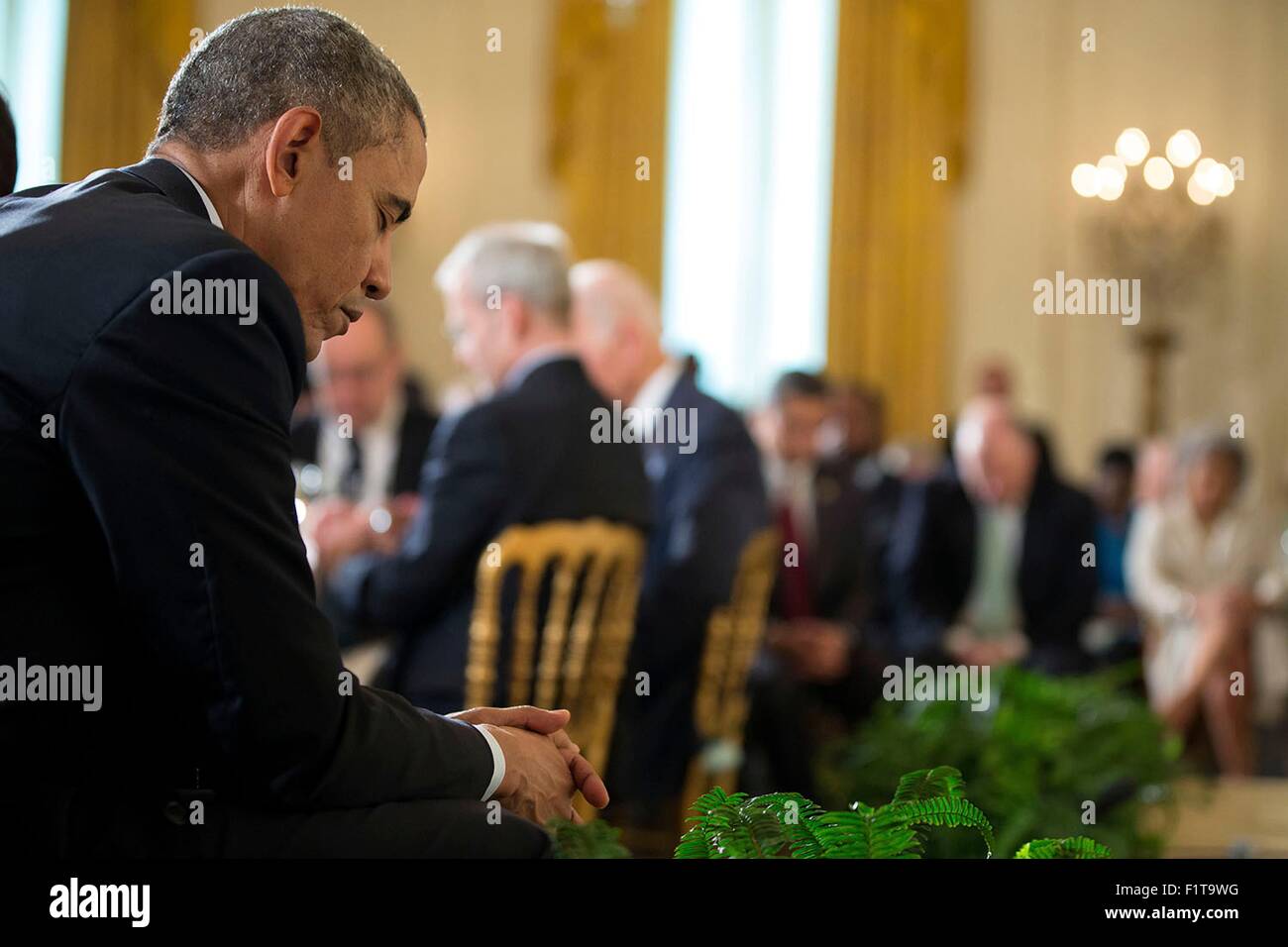 U.S. President Barack Obama bows his head for the closing prayer at the Easter Prayer Breakfast in the East Room of the White House April 7, 2015 in Washington, DC. Stock Photo