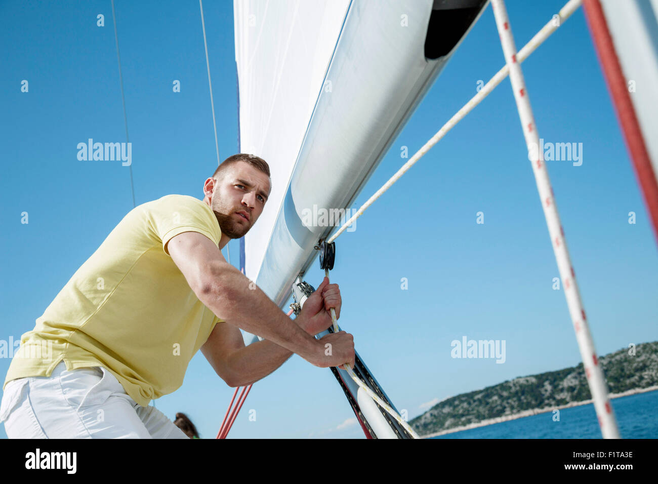 Man adjusting sail on sailboat, Adriatic Sea Stock Photo