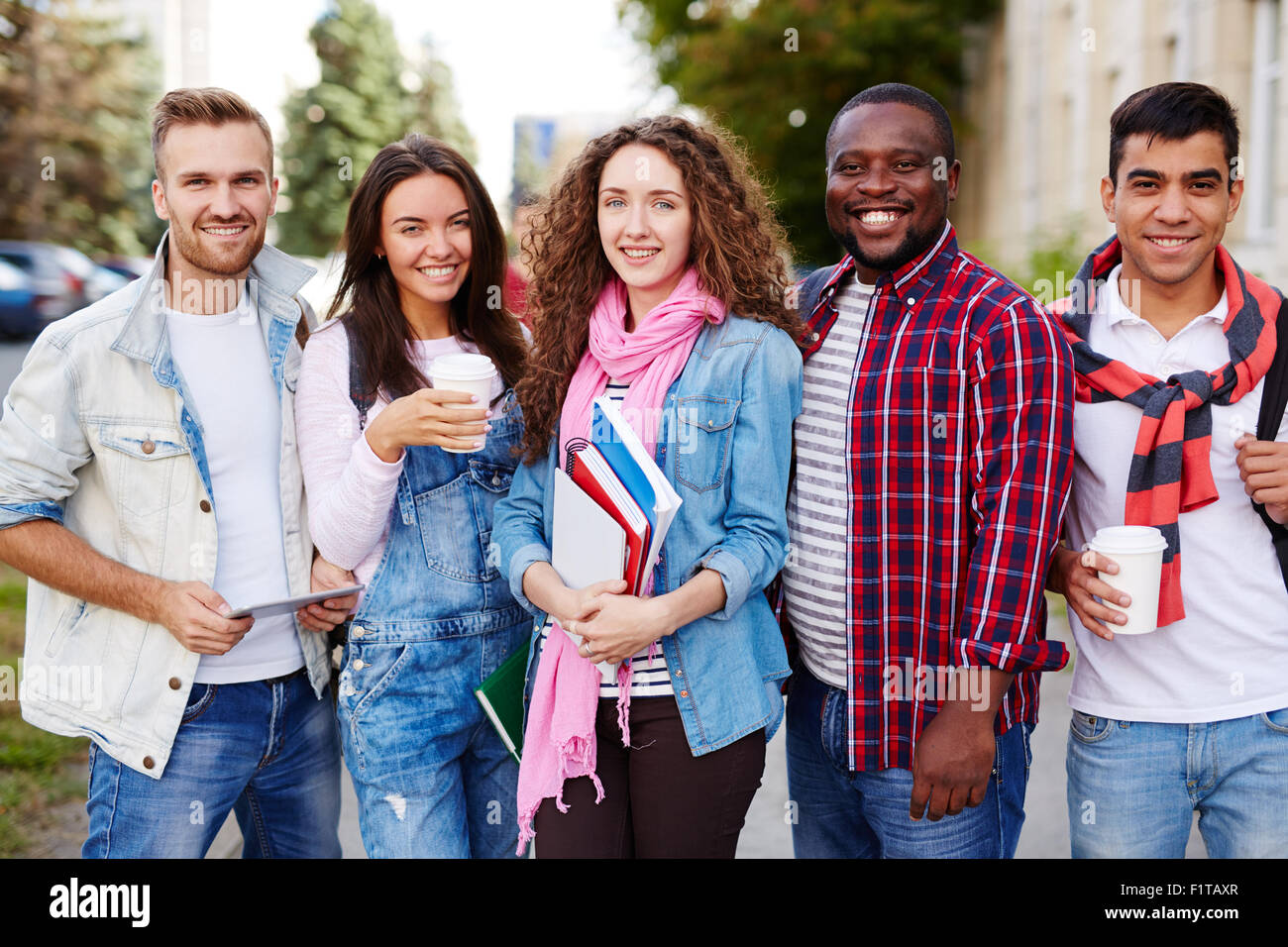 Friendly high school learners looking at camera outdoors Stock Photo