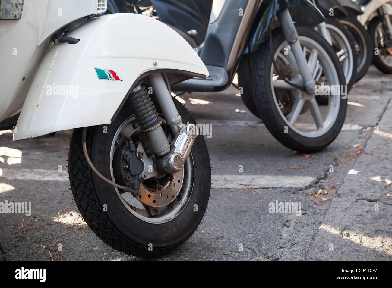 Ischia, Italy - August 15, 2015: Classic old style Vespa scooters stands parked on a roadside, fragment with front wheels Stock Photo