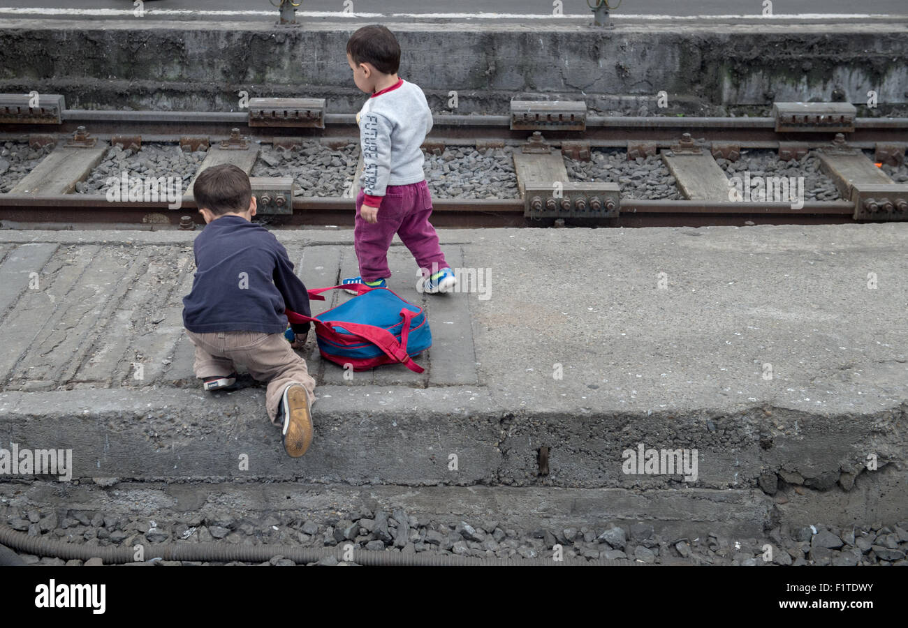 Two children climb over the train tracks as they wait to continue their ...