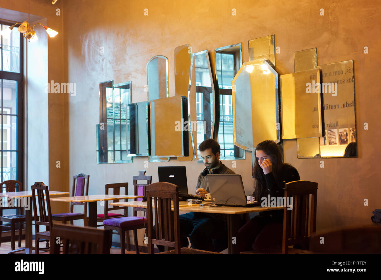 Young man and young woman working on computers in a Porto cafe. Stock Photo