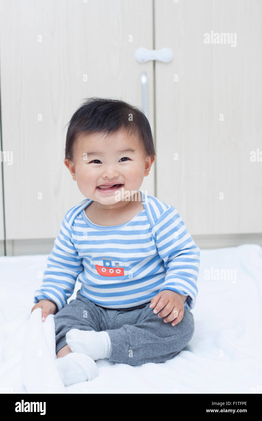 Cute Chinese baby boy sitting on a white blanket Stock Photo