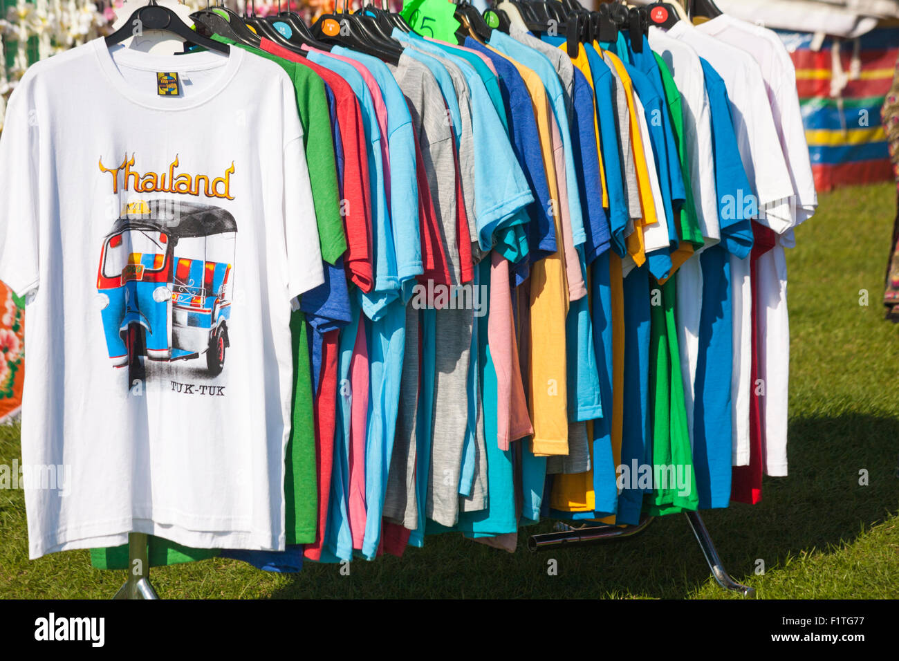 Row of t-shirts for sale hanging on rail on stall at Poole Thai Festival, Dorset, UK in September Stock Photo