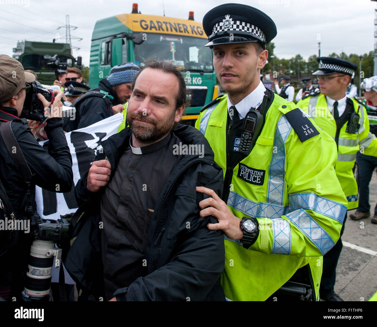 London, UK. 7th September, 2015. Police remove a vicar from the blockade during a protest against the DSEI, one of the worldÕs largest arms fairs. Activists are angered by the impact they claim the fair has on the Òarms trade and repression.Ó The protesters aim to hold a week of action against the fair to disrupt the smooth running of the event which is scheduled to take place from the 15th to the 18th of September 2015 at the ExCel Centre, Royal Victoria Dock. Credit:  Pete Maclaine/Alamy Live News Stock Photo