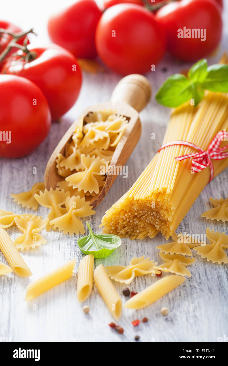 raw pasta spaghetti farfalle penne, tomatoes. italian cuisine Stock Photo