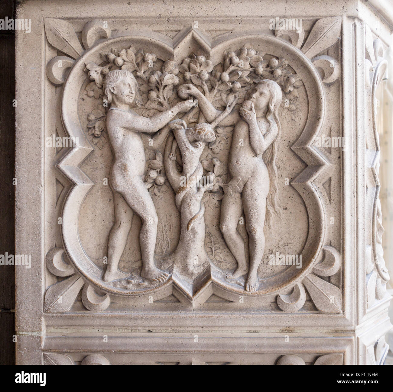 Relief carving of Adam, Eve and the Tree of Knowledge. Eve eats an apple with Adam looking on with a serpent Stock Photo