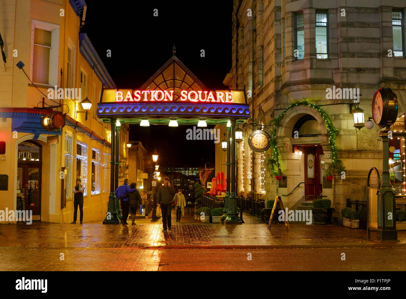 Pedestrians walking in Bastion Square in downtown Victoria on rainy wet night-Victoria, British Columbia, Canada. Stock Photo