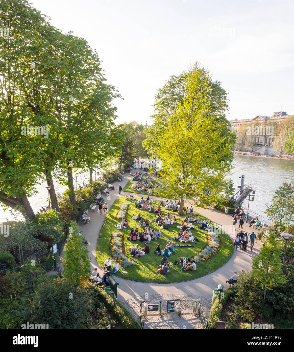 Park at the tip in the Seine . Tourists and locals enjoy the evening sunshine at the tip of the Île de la Cité in the center of Stock Photo