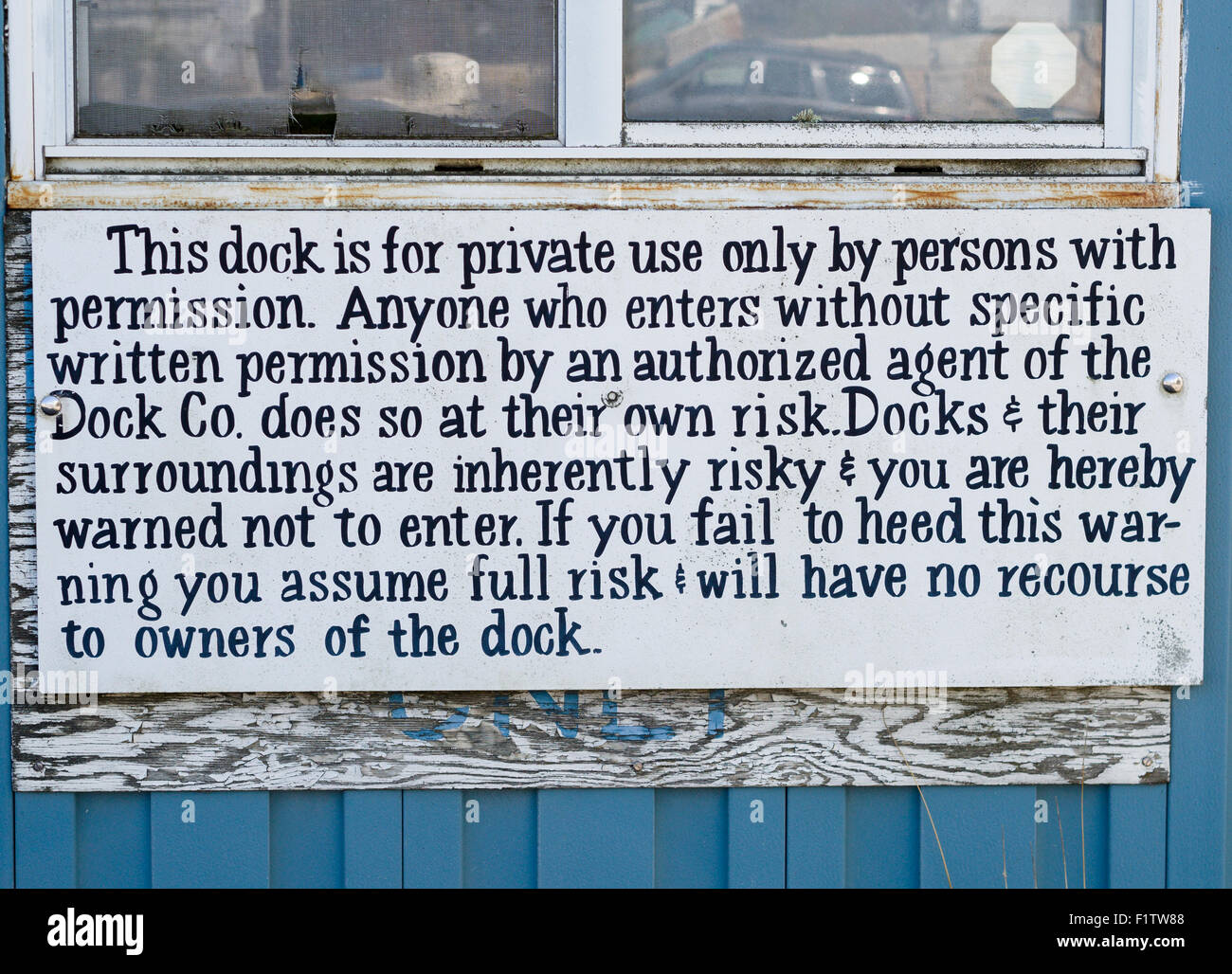 Lawyer inspired sign. A sign with detailed message about trespass and risk, probably replacing a simpler one faded below. Stock Photo