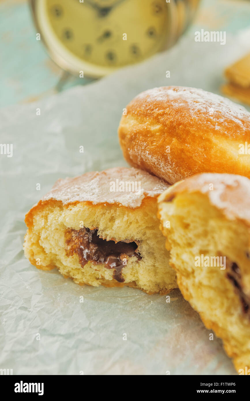 Macro shot of sweet sugary donuts filled with chocolate cream on rustic wooden kitchen table, tasty bakery doughnuts, selective Stock Photo